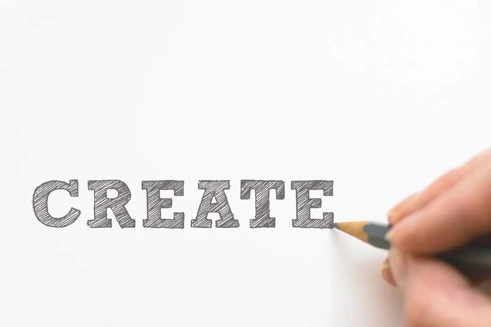 Hand drawing the word CREATE with a pencil
